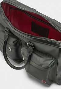 Graue Nylon-Tasche mit Lederakzenten, zwei Vorderfächern, Reißverschlussverschluss und einem tiefroten Innenfutter. Verfügt über robuste Griffe.