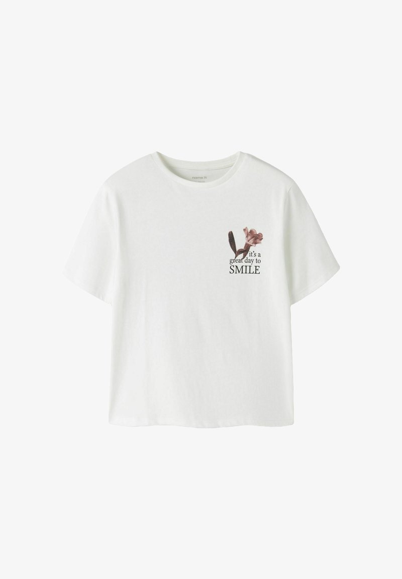 T-shirt blanc à manches courtes avec un petit motif floral et le texte "it's a great day to SMILE" en haut à gauche.