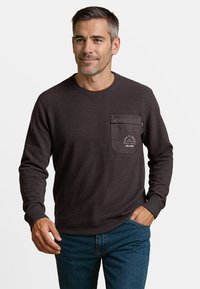 Donkerbruin sweatshirt met lange mouwen en een gestructureerde afwerking, voorzien van een borstzak, een klein logo-detail en geribbelde manchetten en halslijn.