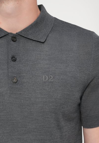 Grå polo skjorte lavet af et tekstureret stof, med en krave, tre sorte knapper, og prægede "D2" på venstre side.