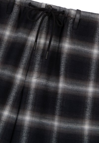 Shorts a quadri neri e grigi con vita regolabile, caratterizzati da un tessuto testurizzato e un piccolo dettaglio con bottone sul davanti.