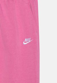 Rozā kokvilnas šorti ar sānu kabatām, ar balto izšuvumu Nike logo kreisajā augšstilbā. Gluda tekstūra un elastīga josta.