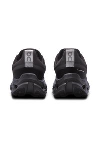 Black athletic shoes with a mesh upper, featuring a textured sole and distinct heel cushioning. Silver accents on the heel and branding.