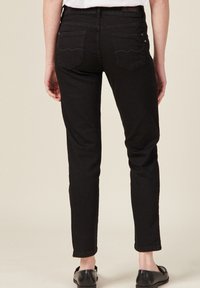 Czarne rurki z denimu. Oferują klasyczny design z pięcioma kieszeniami oraz falistym przeszyciem na tylnych kieszeniach, a także średnim stanem.