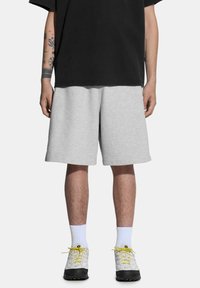Szare krótkie spodenki dresowe o luźnym kroju, wykonane z miękkiego materiału. W zestawieniu z czarną, oversize'ową koszulką oraz strukturalnymi białymi i czarnymi sneakersami.