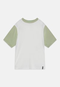 Tričko s krátkým rukávem s bílým tělem a světle zelenými raglánovými rukávy. Hladká textura s kulatým výstřihem a malou logem štítkem na spodní části.
