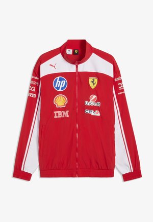 Rød og hvid Puma Ferrari racingjakke med sponsorerlogoer inklusive HP, Shell, IBM, UniCredit og CEVA på fronten og ærmerne.