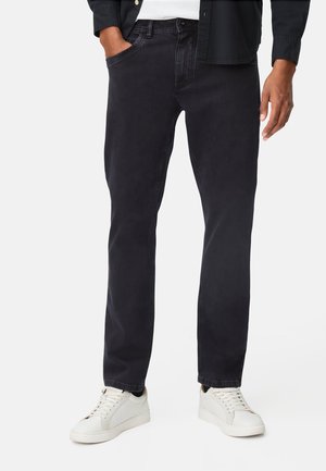 Donkergewaste spijkerbroek van denim, met een rechte pasvorm, contrasterende stiksels en voorzakken. Gecombineerd met witte sneakers.