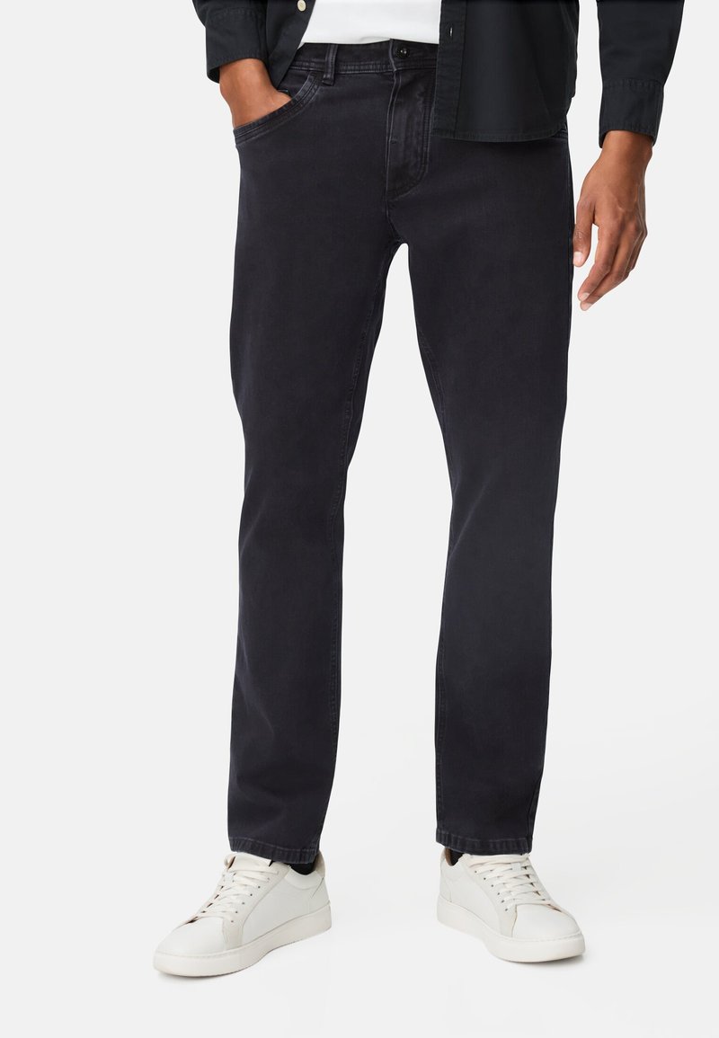 Donkergewaste spijkerbroek van denim, met een rechte pasvorm, contrasterende stiksels en voorzakken. Gecombineerd met witte sneakers.