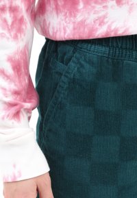 Rosa och vit tie-dye långärmad tröja i kombination med mörkblå kordflortsbyxor med mönstrad textur och sidofickor.