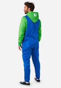 Un mono con capucha en azul y verde, de textura suave, con un gran bolsillo frontal y un logo en la parte posterior. Decorado con zapatos negros.