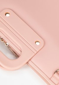 Rosa Lederhandtasche mit einem auffälligen Griff, Reißverschlussverschluss und goldfarbenen Hardware-Akzenten, mit einer glatten, strukturierten Oberfläche.