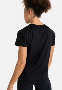 Kortærmet sort trænings T-shirt lavet af blødt stof, med rund halsudskæring og en afslappet pasform, i en glat tekstur uden synlige mønstre.