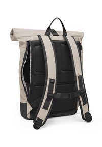 Sac à dos roll-top en beige et noir, doté de bretelles en mesh réglables et rembourrées ainsi qu'une poche latérale zippée pour un accès facile. Matériau durable.
