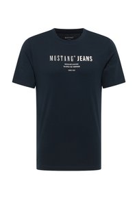 Námorně modré bavlněné tričko s kulatým výstřihem a krátkými rukávy. Na přední straně jsou bílé nápisy "MUSTANG JEANS" a další prvky značky.