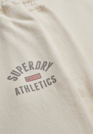 Beige Superdry Athletics sweatpants met elastische tailleband en bedrukt logo met een klein rood-wit gestreept rechthoek. 