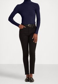 Marinblå ribbad polotröja, högmidjade svarta skinny jeans, svart bälte med cirkulär spänne och svarta loafers med logodetalj.