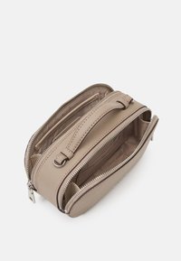 Béžová kabelka z umělé kůže se dvěma zipovými přihrádkami, horním uchem a látkovou podšívkou. Hladký povrch a stříbrné kovové detaily.