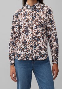 Camicia a maniche lunghe con bottone, a fantasia floreale su fondo bianco, con accenti in blu navy, arancione e marrone. Maniche lunghe con polsini a bottoni.