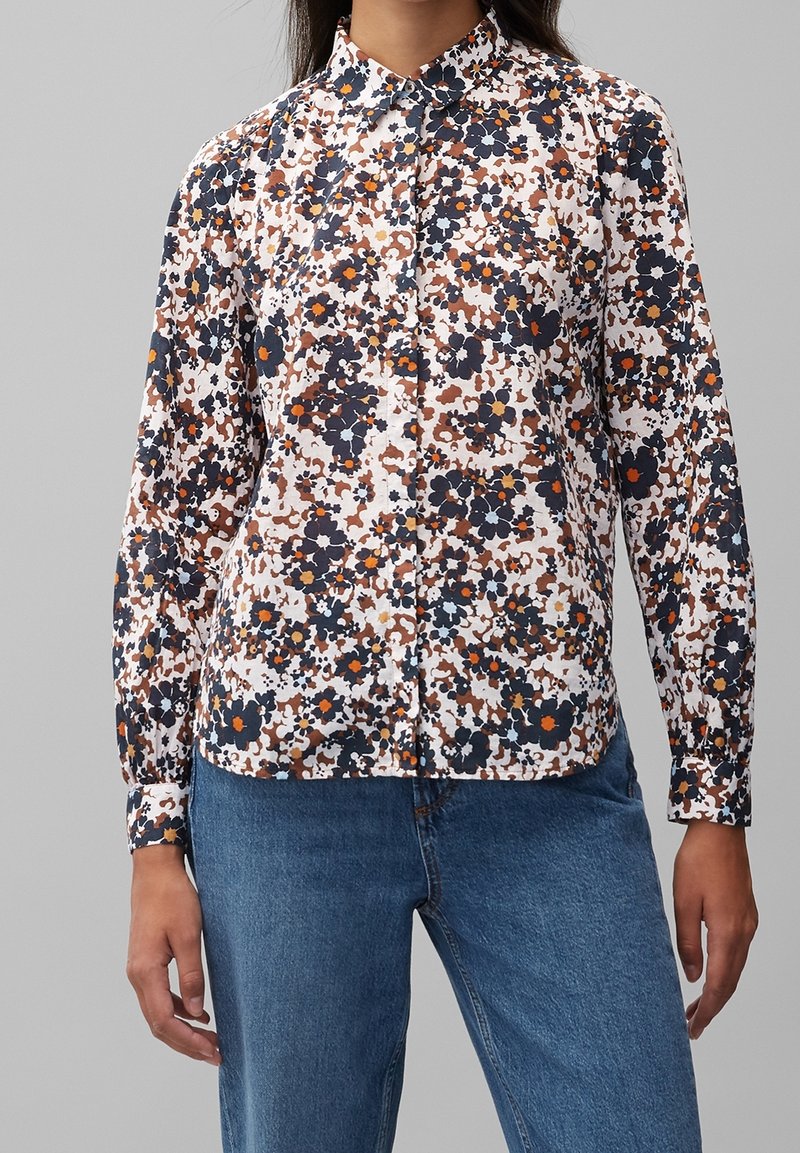 Camicia a maniche lunghe con bottone, a fantasia floreale su fondo bianco, con accenti in blu navy, arancione e marrone. Maniche lunghe con polsini a bottoni.