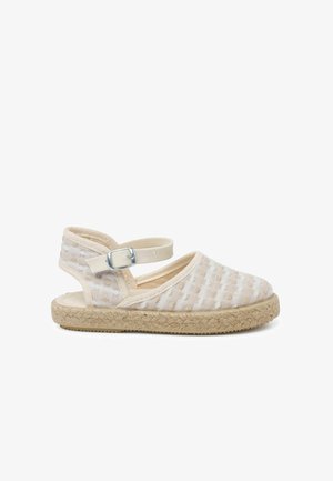Sandalo espadrille con tomaia in tessuto beige intrecciato, cinturino alla caviglia elastico in tonalità chiara e suola con texture di juta.