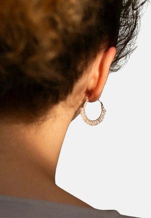 Orecchini a cerchio con finitura in oro rosa e accenti di perline trasparenti, caratterizzati da una forma circolare e una texture liscia.