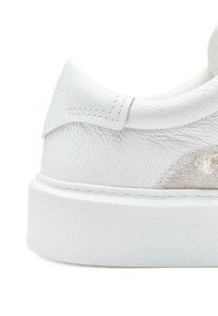 Białe sneakersy z chropowatą skórzaną cholewką, gładkimi akcentami, podwyższoną piętą i płaską gumową podeszwą z subtelnymi detalami szycia.