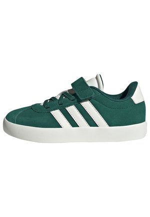Zapatillas de gamuza verde con suela de goma blanca, que cuentan con tres rayas blancas, cordones y una correa de gancho y bucle. Punta redondeada y cuello acolchado.