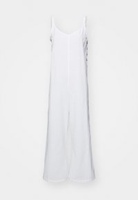 Mono de lino blanco con piernas anchas, tirantes de camisola y escote recto. Presenta una costura central y un diseño minimalista.
