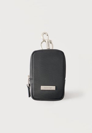 Compact zwarte Calvin Klein pouch met ritssluiting en zilveren clip om aan tassen of riemen te bevestigen, geschikt voor het bewaren van kleine items.