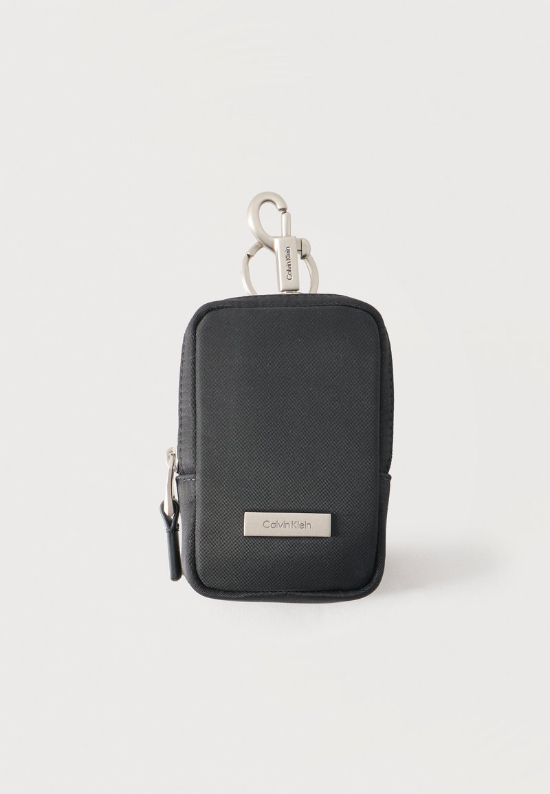 Μικρό μαύρο πουγκί Calvin Klein με φερμουάρ και ασημένιο κλιπ για προσάρτηση σε τσάντες ή ζώνες, κατάλληλο για αποθήκευση μικρών αντικειμένων.