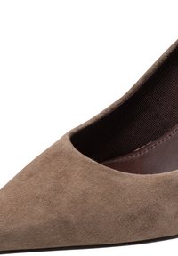 Gros plan d'une chaussure plate en daim marron à bout pointu avec une doublure en tissu côtelé foncé et une finition intérieure lisse.