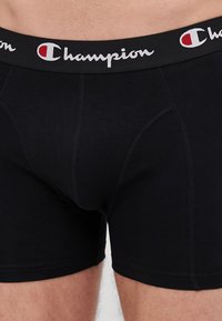 Sorte bokserbrief i sort, laget av myk stoff med en tettsittende design og elastisk midje med "Champion"-logo i kontrasterende hvit brodering.