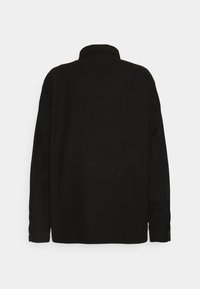 Effen zwart langemouwen shirt met knoopmanchetten, gezien van de achterkant tegen een witte achtergrond.