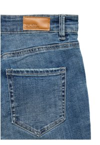 Jean en denim avec une teinte bleu clair, étiquette en cuir portant "VERO MODA WE DO DENIM", poche arrière avec un détail de couture classique.