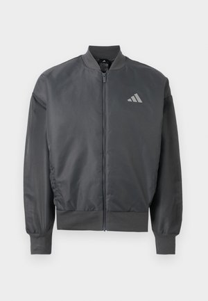 Tamnosiva bomber jakna na patentni zatvarač s rebrastim ovratnikom, manžetama i rubom, s malim Adidas logom na lijevoj strani prsa.