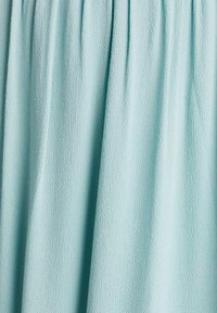 Tissu texturé bleu clair avec de subtils plis verticaux créant des plis doux et un motif de surface légèrement ondulé.