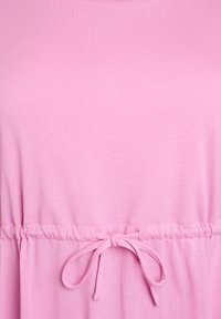 Robe en coton rose avec une taille à cordon de serrage, présentant une texture lisse et des manches courtes. Détail notable : un nœud noué à la taille.