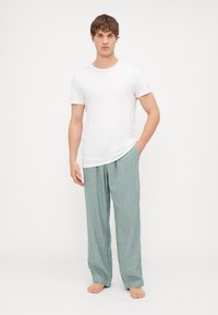 Valge puuvillane T-särk, millele on sobitatud helesinised triibulised ööriided. Pükstel on vertikaalsed triibud ja need on lõdva istuvusega.