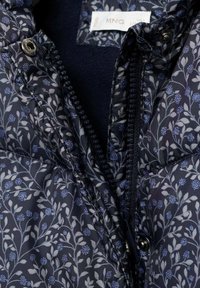 Giubbotto imbottito navy con motivo floreale in azzurro chiaro e grigio. Presenta una chiusura con zip e bottoni a pressione sul colletto. Fodera interna morbida.