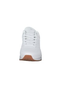 Sneaker Skechers bianco con design allacciato, superiore in sintetico liscio, accenti perforati e suola in gomma marrone chiaro.
