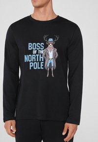 Černá košile s dlouhým rukávem s kresleným jelenem v brýlích a klobouku, s textem "BOSS SEVERNÍHO POLE" v modré barvě.