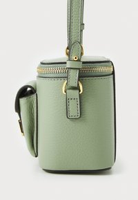 Grønn skinnhandbag med teksturert overflate, gullglidelås og justerbar stropp. Kompakt sylinderform med sidelomme.