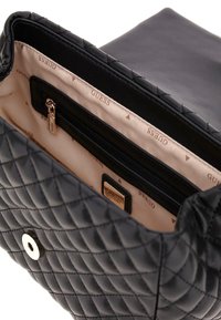 Borsa a tracolla nera trapuntata con fodera interna liscia, tasca con zip e dettaglio del logo. Include una chiusura con calamita.
