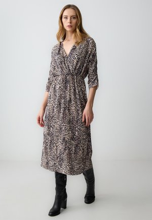 Leopardenmuster-Midi-Kleid mit V-Ausschnitt und geknotetem Taillenbereich, langen Ärmeln, fließendem Stoff, kombiniert mit knielangen schwarzen Stiefeln.