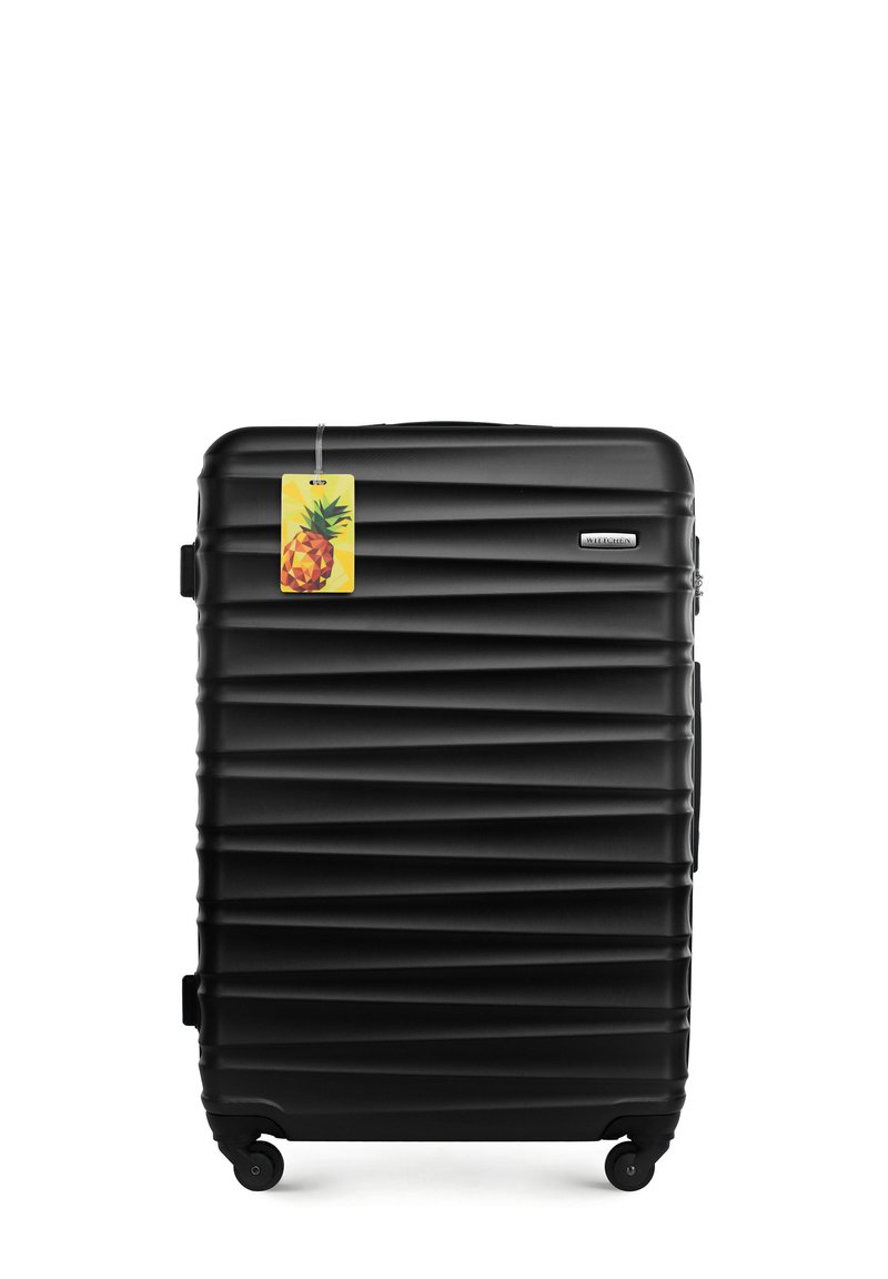 Valise rigide noire avec texture striée, surface lisse et quatre roues. Comprend une étiquette jaune avec un motif d'ananas.