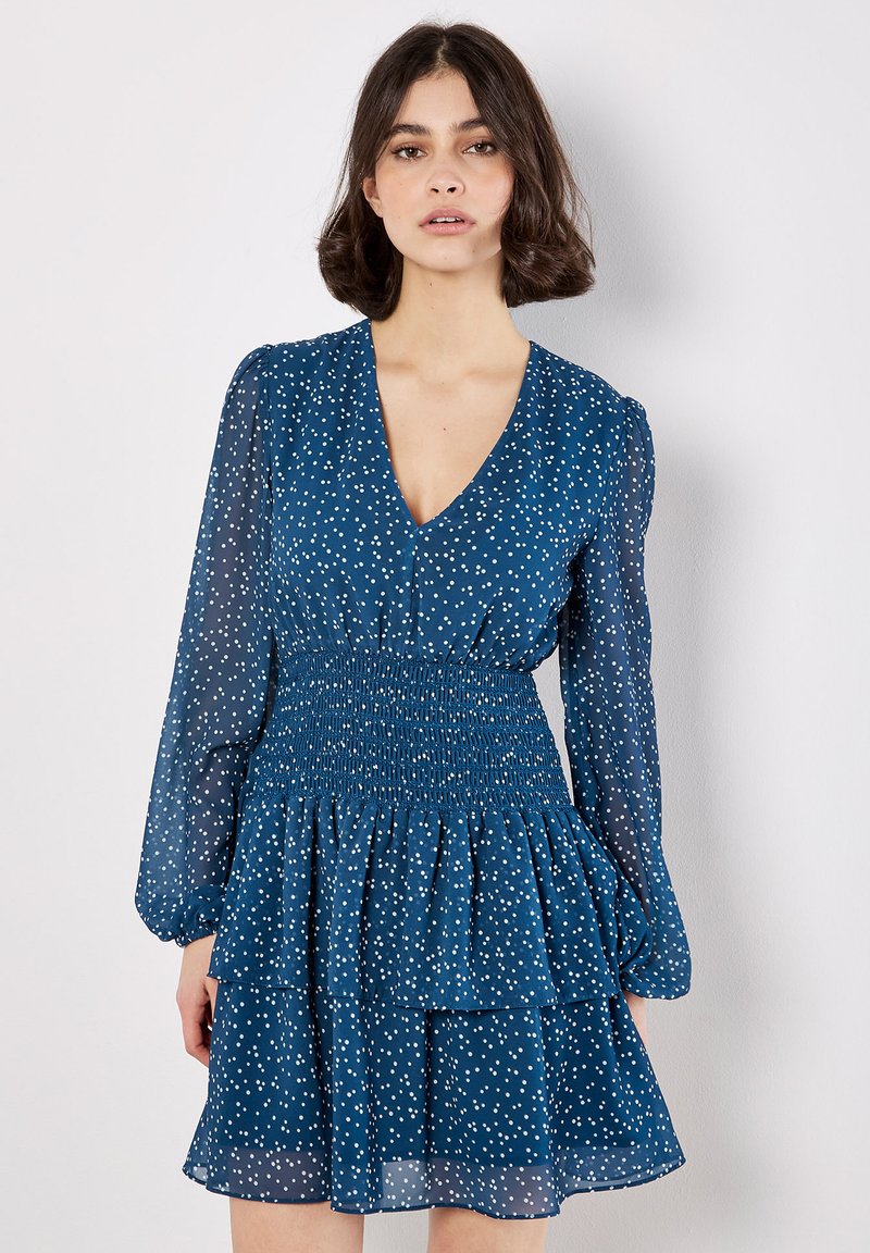 Blaues Blumenkleid mit V-Ausschnitt, langen transparenten Puffärmeln, gerafftem Oberteil und mehrlagigem Rüschensaum mit weißen Punkten.