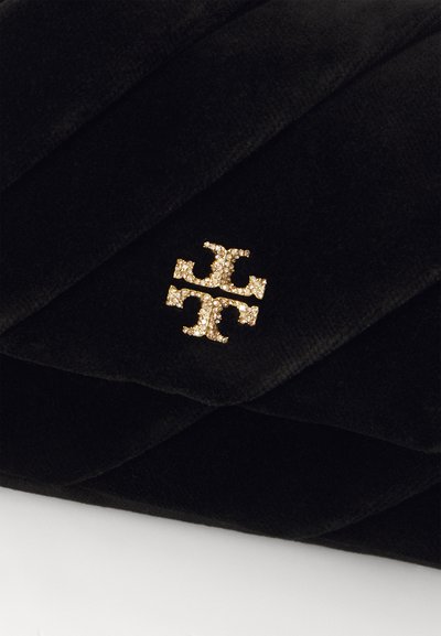 Borsa a tracolla nera trapuntata con un logo dorato in evidenza decorato con strass. Texture morbida e design elegante.