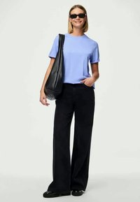 Light blue short-sleeve shirt paired with high-waisted black wide-leg pants. Accessorized with a black tote bag and dark sunglasses.