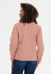 Ljust rosa, strukturerad fleecejacka med rund halsringning och långa ärmar. Har en liten logotypapplikation på den övre vänstra ärmen.